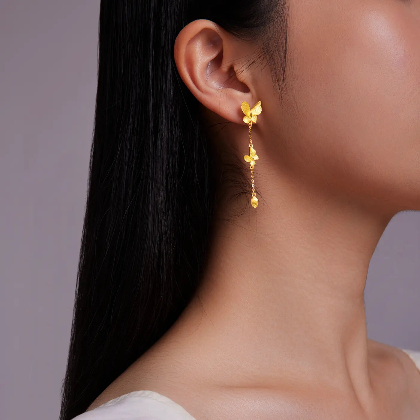 Close-up of a person wearing gold butterfly earrings
