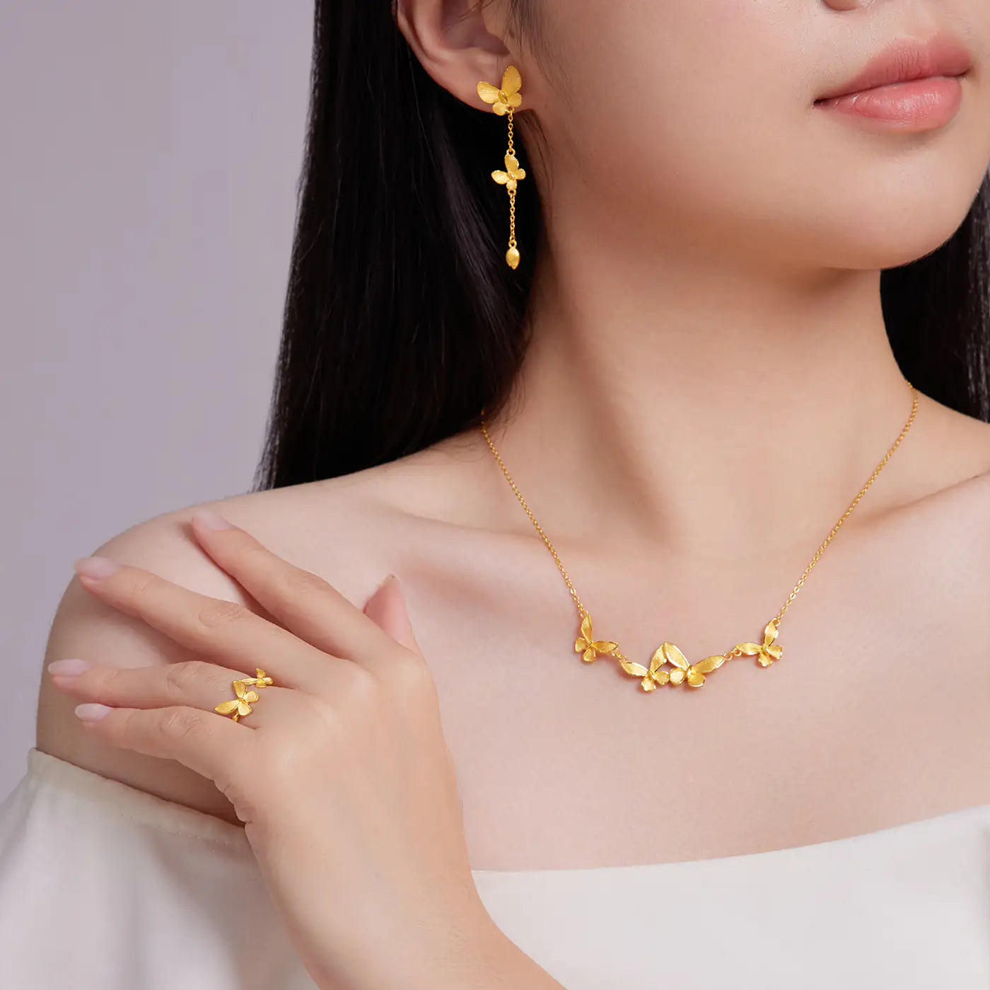 Woman wearing a gold butterfly necklace, earrings, and ring