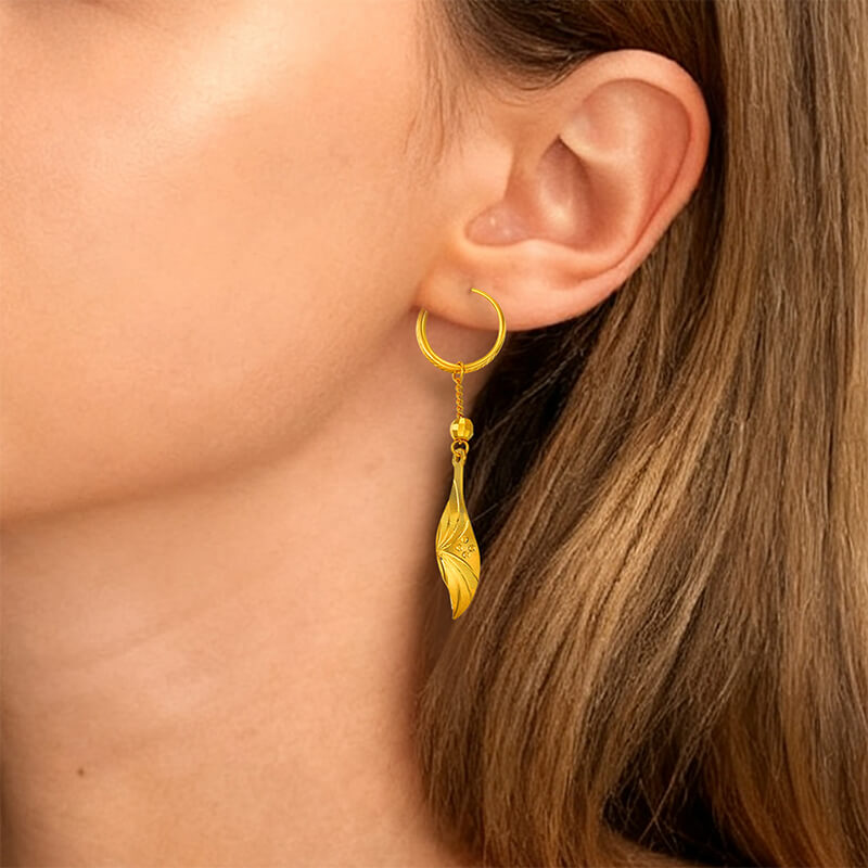 Sunfeel Jewelry 24K Gold hoop earring with a dangling leaf design worn by a person.